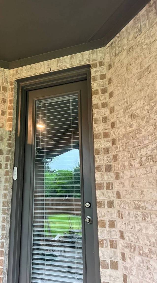 Finished full-glass door with dark trim set into the brick