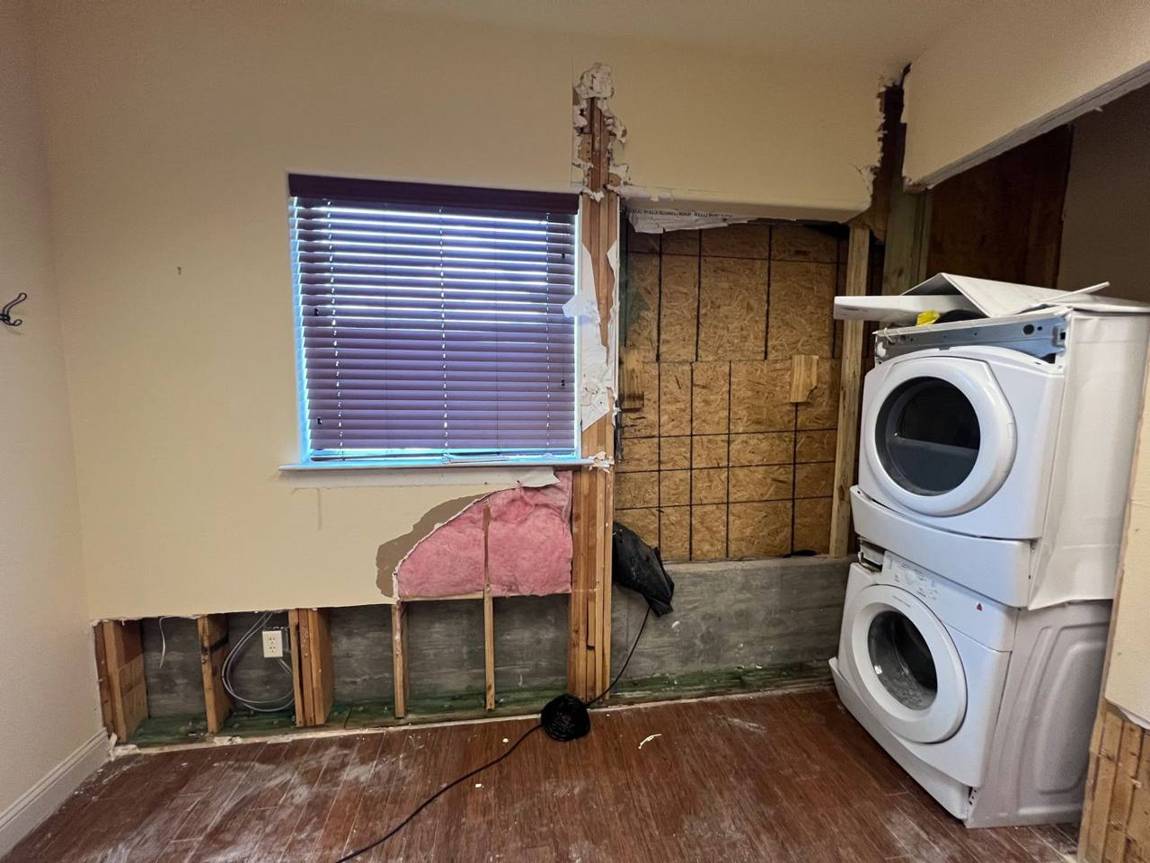 Laundry room wall opened up showing damaged framing and sheathing