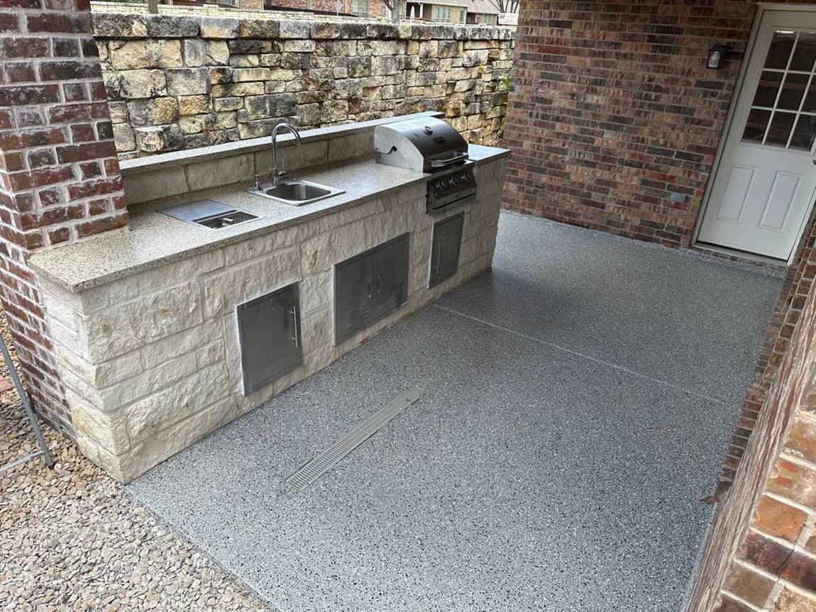 Outdoor kitchen patio with a new gray flake epoxy floor and trench drain