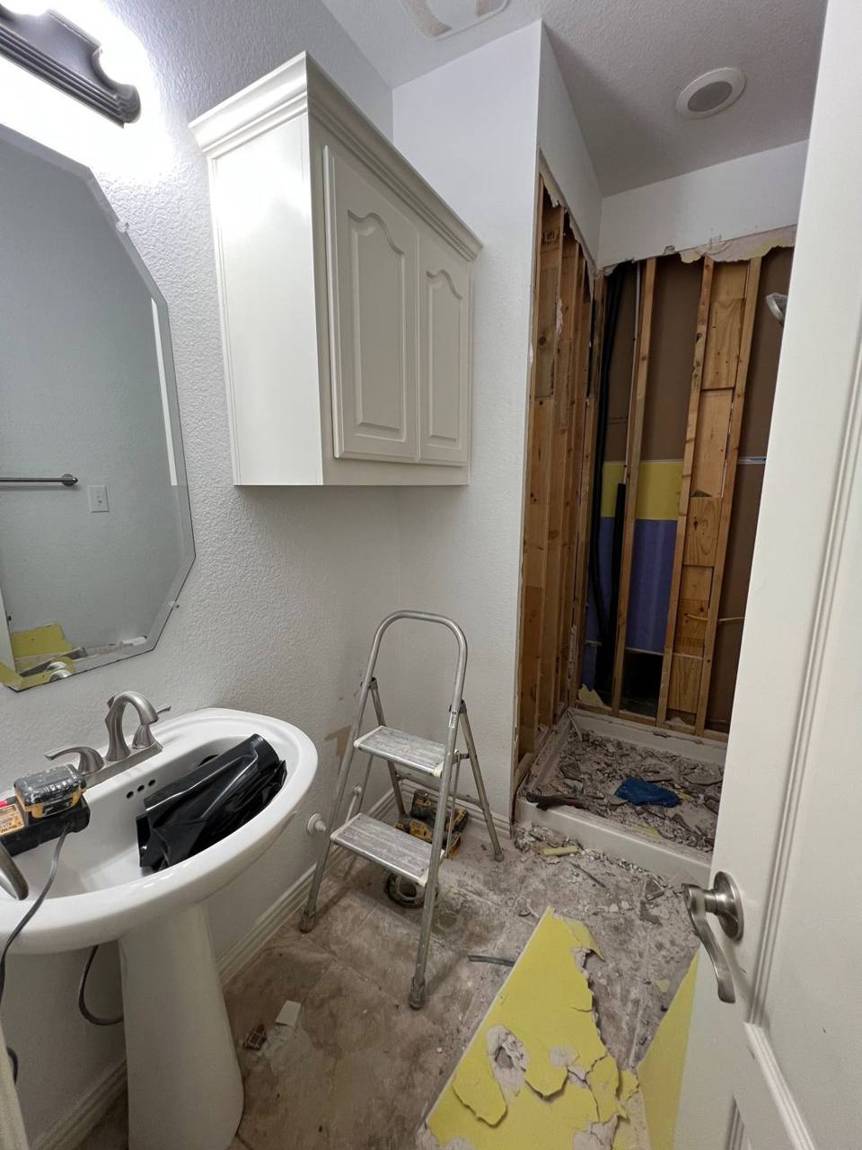 Bathroom during demolition with the old shower stripped to the studs
