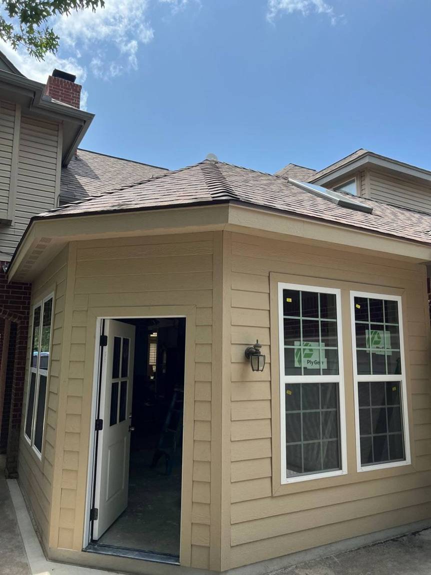 Finished exterior of the addition with siding, a new door, double windows, a skylight and a matching roof
